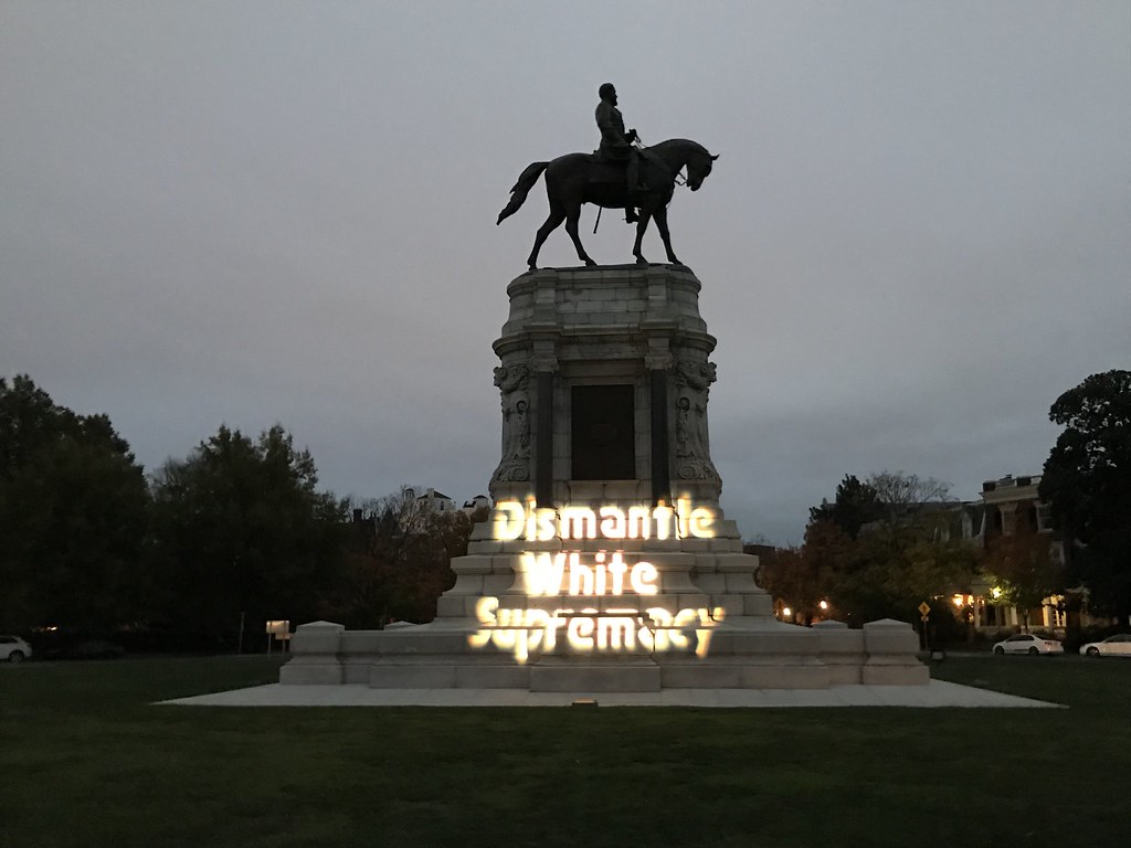 Monument of a man on a horse with the words dismantle white supremacy in white text